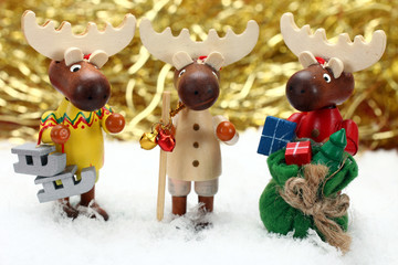 drei witzige Dekoelche stehen im Schnee, goldener Hintergrund