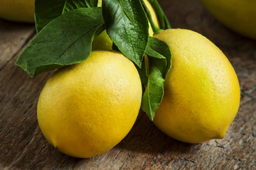 Fresh juicy lemons with leaves on the old wooden table, selectiv