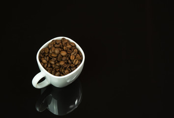 White cup with coffee grains on isolated black