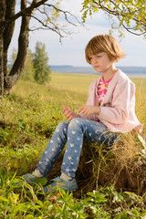 The girl with short blond hair sitting on the grass