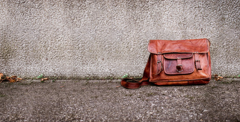 schicke braune ledertasche steht angelehnt an einer wand auf dem boden