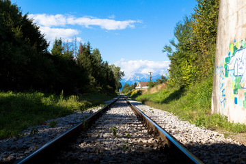 Fototapeta premium Railway going into the distance to the massive mountains.