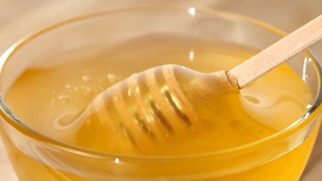 Using spoon for honey in bowl, pick it up, close up, slow motion