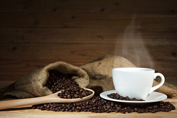 Coffee cup and coffee beans on wooden background.