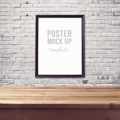 Poster mock up template with wooden table over brick white wall