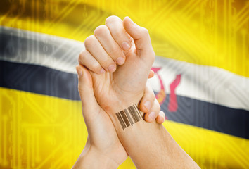 Barcode ID number on wrist and national flag on background - Brunei