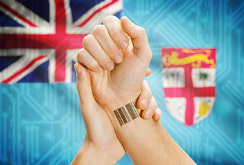 Barcode ID number on wrist and national flag on background - Fiji