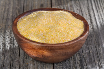 corn grits polenta in a wooden bowl on old wooden table