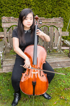 Serious Teen Musician Playing Cello Outside On Old Wooden Swing. Vertical.