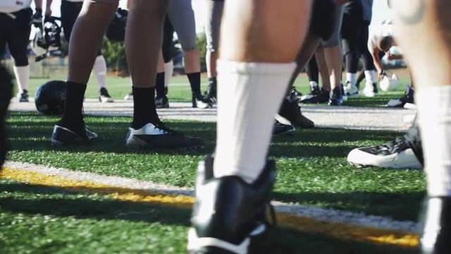 Football players standing around before a game, close up on the cleats
