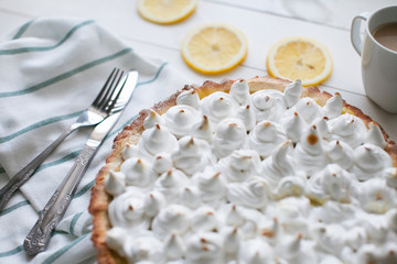 lemon tart with meringue on a table with a napkin and appliances