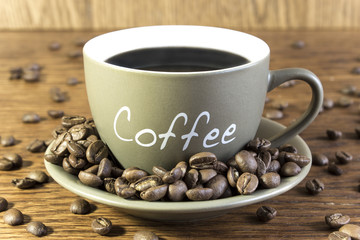 Cup of coffee with beans standing on a wooden table. Blurred, focus on mug