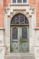Fototapeta na wymiar old steel door with decorative pattern in neogothic stone portal