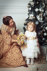 Child with mother receiving near Christmas tree.