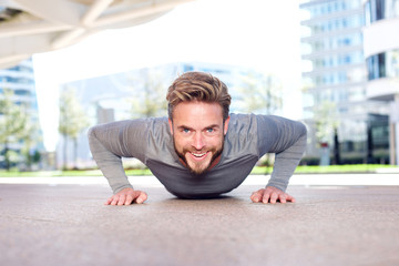Smiling man doing push ups outdoors in the city