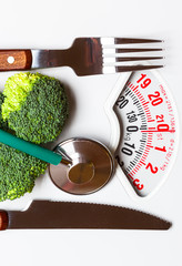 Broccoli with stethoscope on weight scale. Dieting