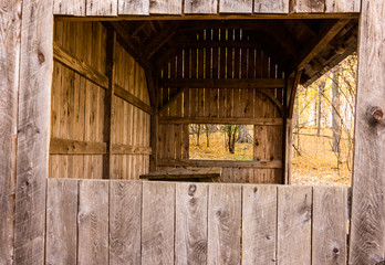 looking through the covered shelter where children can sit at the picnic table to work on projects in the woods at educational center 
