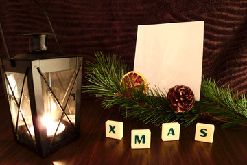 Xmas word with white paper, flashlight candle, pine branch and orange. Christmas still life.