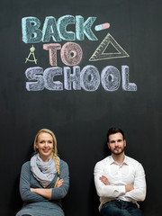 Portrait of a smiling young man and woman in front of chalkboard