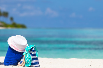 Fototapeta na wymiar Stripe bag, blue towel, sunglasses, sunscreen bottle and swimsuit on white beach