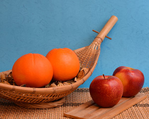 Apples and oranges fruits on wooden bowl on a blue background