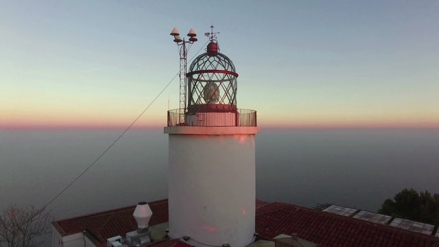 Maritime Lighthouse Aerial Shoot View at Sunset.Mediterranean maritime lighthouse next to the sea.Awesome sunset over the Mediterranean Sea.Aerial drone shot flying over the lighthouse.