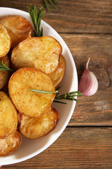 Delicious baked potato with rosemary in bowl on table close up