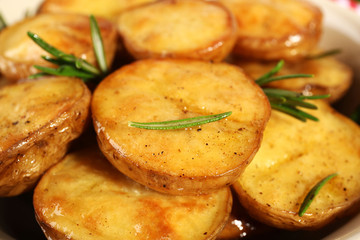 Delicious baked potato with rosemary in bowl close up