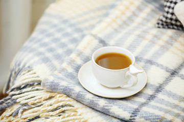 Cup of coffee on sofa in living room