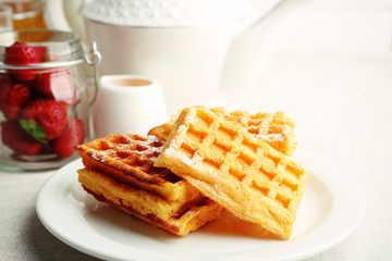 Sweet homemade waffles with fresh strawberries on plate, on light background
