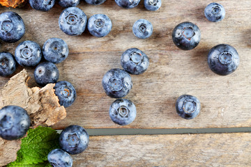 Tasty ripe blueberries with green leaves on wooden table close up