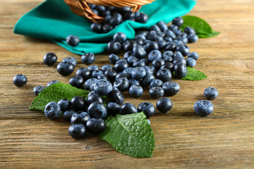 Tasty ripe blueberries with green leaves on wooden table close up