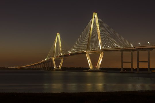 Fototapeta Arthur Ravenel Jr. Bridge illuminated aginst a darkening dusk sky.  The bridge carries eight lanes of traffic over the Cooper River between Charleston and Mount Pleasant, SC.  