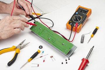Electronics engineer testing a circuit board with a multimeter