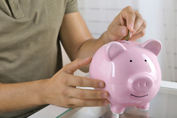 Man put coin into a piggy-bank