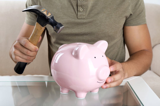 Man with a hammer going to break the piggy bank, close up