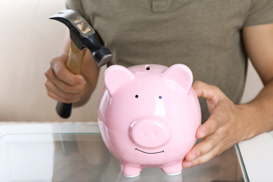 Man with a hammer going to break the piggy bank, close up