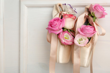 Beautiful ballet shoes with roses in it hanging on white frame background, close up