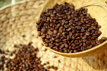 Roasted coffee beans scatter from wattled basket into the other one