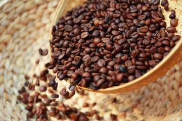 Roasted coffee beans scatter from wattled basket into the other one