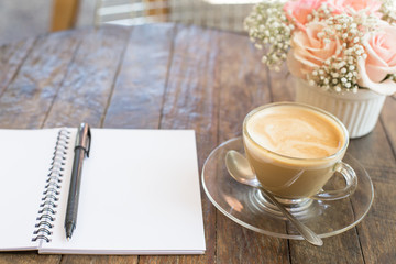 Hot latte art coffee cup on wooden table and note book, vintage
