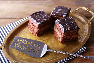 Sweet chocolate cakes and spatula on tray with stripped cotton serviette, close up