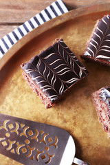 Sweet chocolate cakes and spatula on tray with stripped cotton serviette, close up