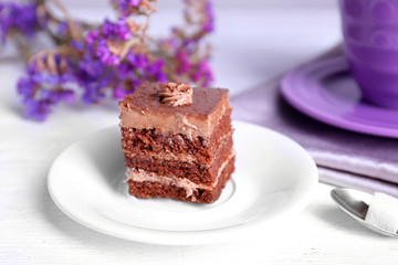 Served table with chocolate cake and a cup of tea on white wooden background