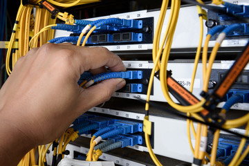 man connecting fiber optic cable to core switch