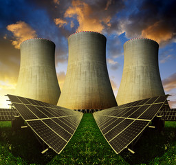 Solar energy panels and nuclear power plant at sunset.