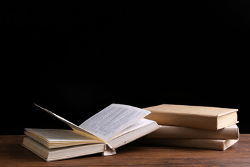Old books on wooden table against black background