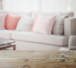 wooden table top with blur of orange and gray pillows setting on