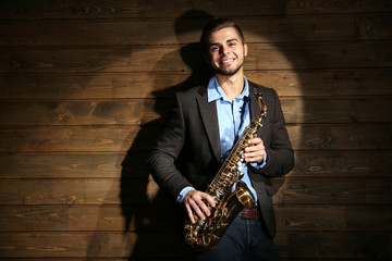 Naklejka premium Elegant saxophonist plays jazz on wooden background
