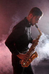 Plakat Young man professionally plays sax in red smoke